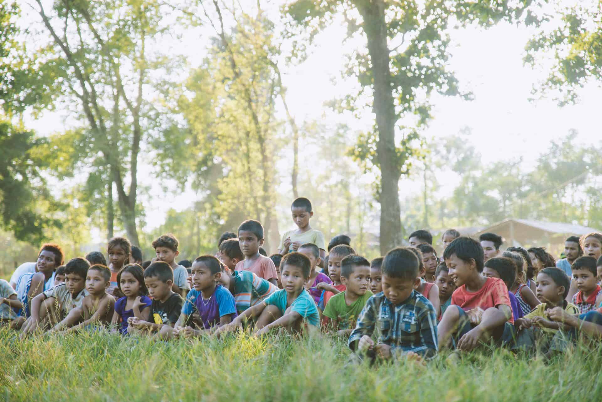Children sit in a field at the Himalayan Life Sport Training & Daycamps in Pokhara, Nepal