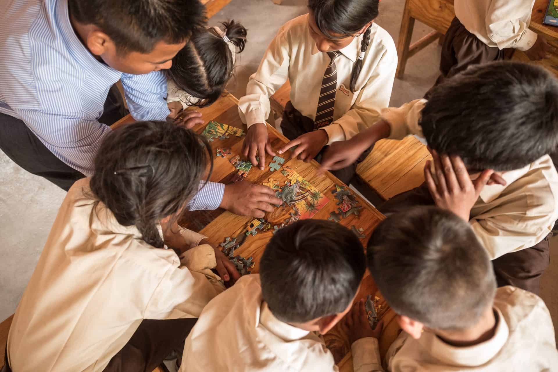 A teacher helps students put together a puzzle at the Yangri Academic Center