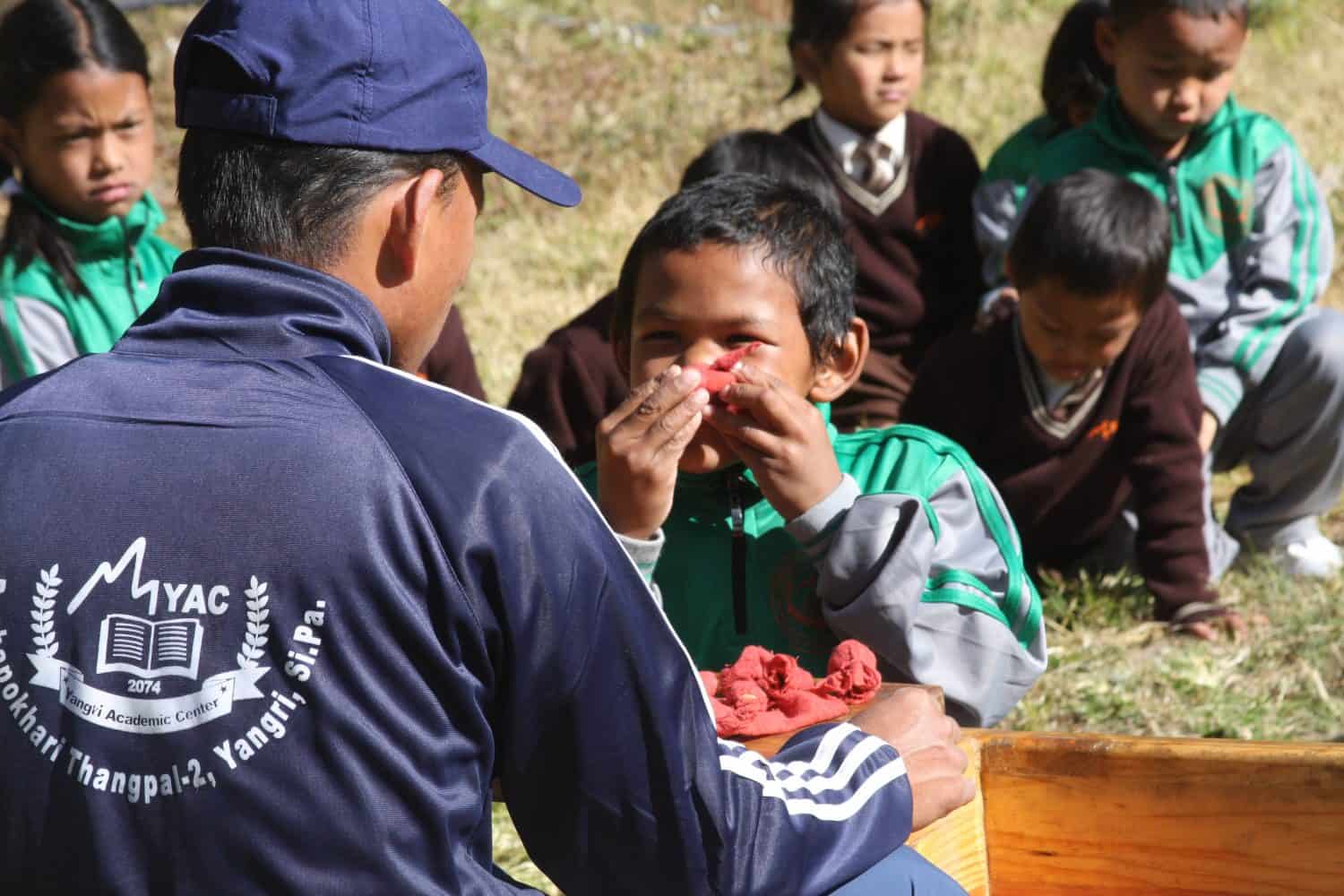 A young orphan boy in Nepal smells fresh flowers during Himalayan Life's Project Week