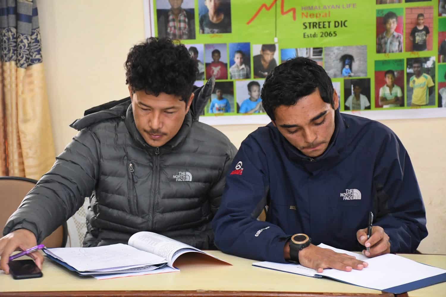 Two Himalayan Life staff members study through the workbook that was handed out during the conference