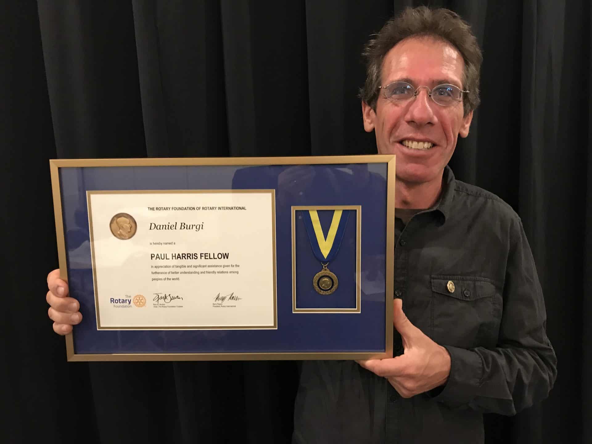 Himalayan Life CEO and Founder Daniel Burgi holds up the Paul Harris Fellow Rotary Award and medal